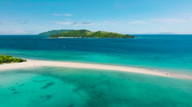 Yakınındaki yemyeşil yemyeşil sularda canlı turkuaz sularda el değmemiş beyaz bir kumluk uzanır. Bon Bon Plajı, Romblon, Filipinler.