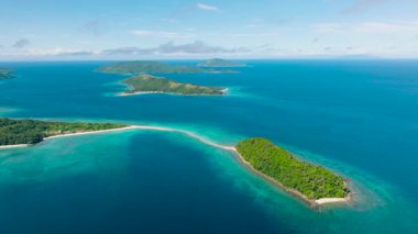 Parlak bir gökyüzünün altındaki yemyeşil adaları çevreleyen berrak turkuaz sular. Romblon, Filipinler.