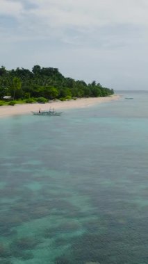 Okyanus dalgaları beyaz kuma çarpıyor. Mercanlı turkuaz su üzerinde tekne. Santa Fe, Tablas, Romblon. Filipinler. Dikey görünüm.