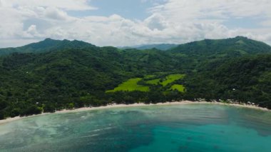 Plajda yumuşak beyaz kum ve mercan resifli turkuaz su bulunur. Yeşillik bitki örtüsü olan el değmemiş bir ada. El Nido, Palawan. Filipinler.