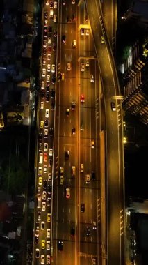 Kalabalık otoyollarda, konut binalarıyla çevrili araçların parlak ışıklarıyla uçan insansız hava aracı. Bangkok, Tayland.