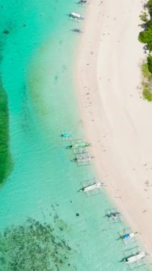 Temiz su ve beyaz kum üzerinde turist botlarıyla kıyı şeridi. Puka Deniz Kabuğu Sahili. Boracay, Filipinler. Dikey görünüm.