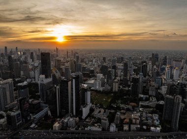 Bangkok 'ta gün batımında gökdelenler ve otoyollar görülebilir, sıcak gökyüzü renkleri şehir silüetiyle harmanlanmış. Bangkok, Tayland.