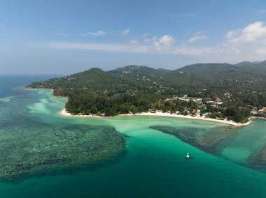 Canlı sularla çevrili tropikal körfezler ve güneşli bir gökyüzünün altında yemyeşil manzaralar. Ko Pha Ngan, Tayland.