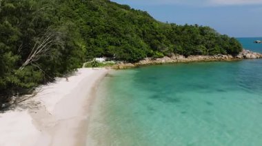 Sessiz, turkuaz suyu olan, yeşil ormanlarla çevrili, güneşli bir gökyüzünün altında kayalık çıkıntılar olan beyaz kumlu bir sahil. Ko Pha Ngan, Tayland.