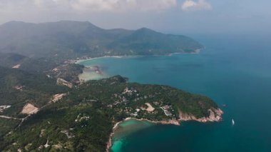 Güneşli bir günde, turkuaz berrak su ve yemyeşil ormanlarla çevrili Rocky sahili. Ko Pha Ngan, Tayland.