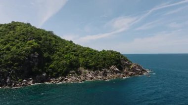 Kayalık kıyı şeridi açık bir gökyüzünün altında derin mavi okyanusla çevrili. Koh Tao, Tayland.