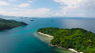 Ada tepeleri canlı yeşil yapraklarla kaplıdır. Turkuaz suları ve mercanları olan tropik beyaz kumsal. Cagbuli Adası. El Nido, Palawan, Filipinler.