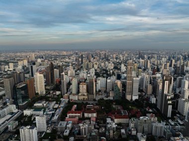 Bangkok 'un gökdelenlerle aydınlanan gökdelenleri ve solan mavi gökyüzünün altındaki yoğun kentsel manzarasıyla akşam manzarası. Bangkok, Tayland.