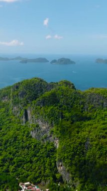 Küçük kasabalı bir ada. Mavi gökyüzü ve bulutlar. El Nido, Palawan. Filipinler. Dikey görünüm.