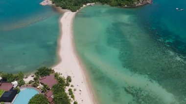 Turkuaz suları ve parlak gökyüzünün altında yemyeşil yemyeşil bir sahil kenarı. Ko Ma Sahili. Ko Pha Ngan, Tayland.