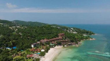 Beyaz bir kumsal ve turkuaz suya bakan yeşillikle çevrili bir tatil köyünün tepe manzarası. Haad Yao. Ko Pha Ngan, Tayland.