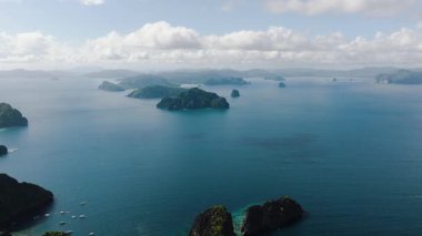 Deniz manzarası, mavi denizle çevrili küçük adaların havadan görünüşü. Kıyıda yüzen turist tekneleri. El Nido, Filipinler.