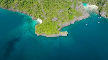 Turkuaz deniz suyunun üzerinde zıplayan tekneler. Kireçtaşı kayalarıyla çevrili tropik bir göl. El Nido. Palawan, Filipinler.