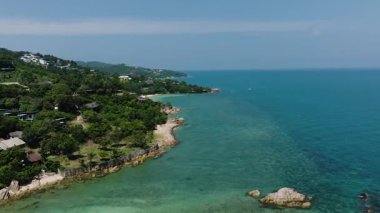 Yoğun ormanlarla kaplı tropikal bir sahil şeridi boyunca turkuaz suların havadan görünüşü. Ko Pha Ngan, Tayland.