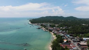 Kıyı köyü yoğun tropikal bitki örtüsü ve parlak bir gökyüzünün altında berrak turkuaz deniz ile çevrili. Ko Samui, Tayland.