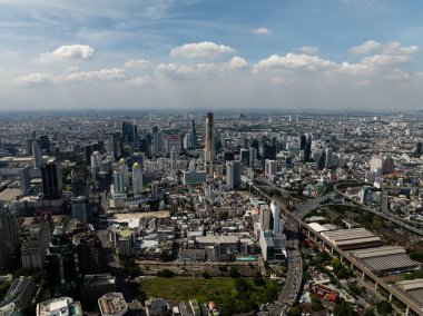 Şehir siluetinin panoramik manzarası şehir yeşilliğini ve parlak gökyüzünün altındaki yüksek binaları vurguluyor. Bangkok, Tayland.