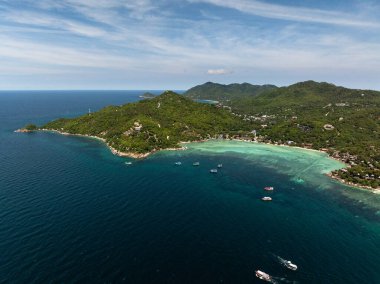 Güneşli bir gökyüzünün altında engebeli uçurumlar, yemyeşil yemyeşil ve turkuaz sulara sahip tropikal kıyı şeridi. Koh Tao, Tayland.
