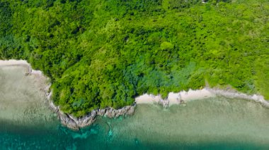 Yumuşak dalgalar yavaşça kayalık kenarlara ve kumlu plaja çarpıyor. Cagbuli Adası. El Nido, Palawan, Filipinler.