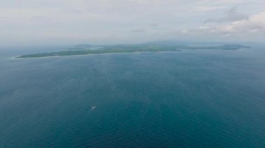 Açık mavi gökyüzünün altında mavi denizle çevrili uzak bir adanın havadan görünüşü. Tablolar Adası, Romblon, Filipinler.