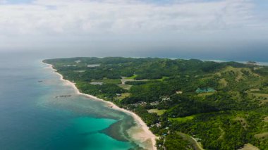 Kıyı manzaralı yeşil tepeler, turkuaz sular ve parçalı bulutlu bir gökyüzünün altında kumlu plajlar. Santa Fe, Tablo, Romblon, Filipinler.