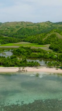 Resiflerin üzerinde beyaz kum ve turkuaz su bulunan tropik plaj manzarası. Santa Fe, Tablas, Romblon. Filipinler. Dikey görünüm.