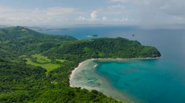 Tepeleri ve vadileri çeşitli yemyeşil bitkiler kaplıyor. Mercanları ve turkuaz suları olan tropik bir sahil. El Nido, Palawan, Filipinler.