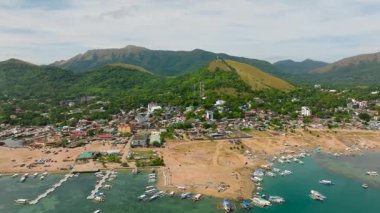 Coron kasabasındaki limandaki binalar ve turist tekneleri dağlık bir geçmişe sahip. Coron, Palawan. Filipinler.