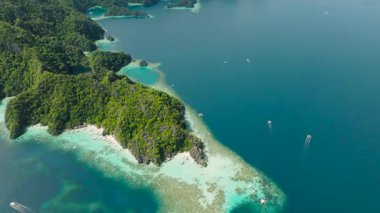 Yeşil tepelerle çevrili kumlu sahildeki teknelerin üst görüntüsü. Banul Plajı. Coron, Palawan, Filipinler.