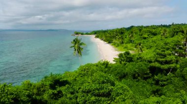 Parlak yeşil kıyı bitki örtüsü, turkuaz okyanus ve mavi gökyüzüne karşı kurulmuş. San Jose, Romblon. Filipinler.