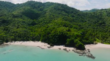 Kumlu sahil etrafındaki tropikal yeşil tepelerin kristal berrak sularıyla hava manzarası. Diapela Sahili. El Nido, Palawan, Filipinler.