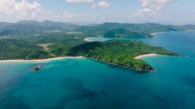 Beyaz kum ve turkuaz suları olan manzaralı bir sahil. El Nido 'daki yemyeşil ormanların tropik manzarası, açık gökyüzü ve bulutlar. Filipinler.