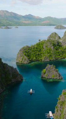 Kireç taşı oluşumları olan bir ada, Kayangan Gölü 'nün etrafında dolaşan tekneler. Coron, Palawan. Filipinler. Dikey görünüm.