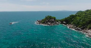 Berrak mavi okyanus suyuyla çevrili yemyeşil bir kayalık ada. Koh Tao, Tayland.