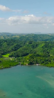 Yeşil bitkileri ve ağaçları olan tropik bir ada. Tekne turkuaz suyun üzerinde. Santa Fe, Tablas, Romblon. Filipinler. Dikey görünüm.