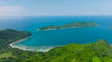 Mavi denizle çevrili tropik adanın insansız hava aracı görüntüsü. Beyaz kumlu sahil şeridi ve mercan resifli turkuaz suları. El Nido, Palawan, Filipinler.