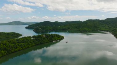 Tekneleri ve yatı olan adaların havadan görünüşü. Sakin okyanus suları, gökyüzü ve bulutların yansımaları. Concepcion, Busuanga, Palawan. Filipinler.