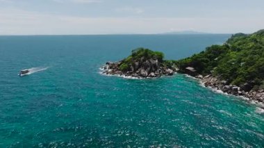 Berrak mavi okyanus suyuyla çevrili yemyeşil bir kayalık ada. Koh Tao, Tayland.