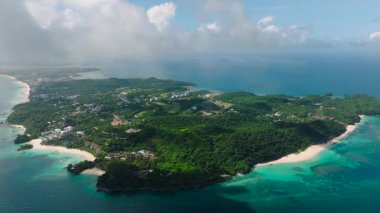 Bereketli yeşillik ve canlı turkuaz sular kıyı şeridi boyunca bulutlu bir gökyüzünün altında. Boracay Adası, Filipinler.
