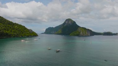 Açık gökyüzünün altında turkuaz su ve tropikal adalar üzerinde küçük tekneler. El Nido Körfezi. Palawan, Filipinler.