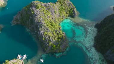 Turkuaz su gölünde mercanlarla yüzen turist tekneleri. Kayangan Gölü. Coron, Palawan. Filipinler.