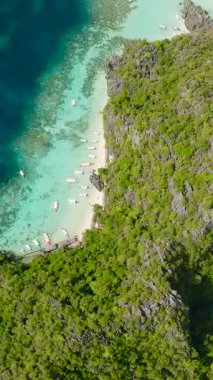 Koron, Palawan 'daki Banul Sahili' nde turkuaz berrak su üzerinde yüzen bir grup tekne. Filipinler. Dikey görünüm.