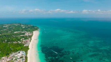 Dağılmış tekneleri ve yeşil tepelerle çevrili beyaz kumlu kıyı şeridi olan el değmemiş turkuaz sular. Bulabog Sahili, Boracay Adası, Filipinler.