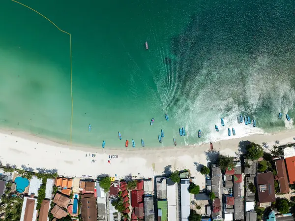Turkuaz suları, beyaz kumlu plajı ve hareketli köy çevresi olan kıyı şeridi yakınlarındaki balıkçı teknelerinin en üst görüntüsü. Haad Rin. Ko Pha Ngan, Tayland.