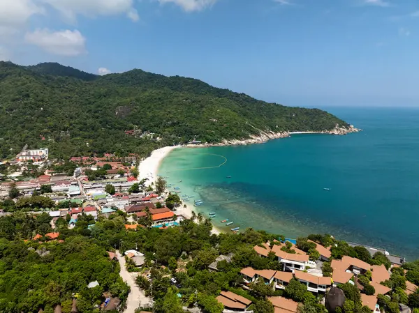 Canlı turkuaz sularda renkli teknelerin bulunduğu ve yemyeşil tepelerle çevrili sahil köyü. Haad Rin. Ko Pha Ngan, Tayland.