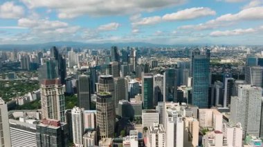 Gökyüzünün altında yeşil alanlarla çevrili uzak şehir binalarının silueti. Metro Manila, Filipinler.