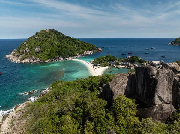 Güneşli gökyüzünün altındaki turkuaz sulara tepeden bakan yemyeşil yemyeşil kayalıklarla çevrili kayalıklar. Ko Nang Yuan, Tayland.