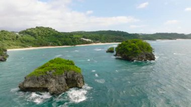 Turkuaz okyanus suları kayalık adaları ve berrak bir gökyüzünün altında yemyeşil bir sahili kuşatır. Ilig Iligan Sahili. Boracay Adası, Filipinler.