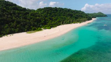 Bereketli tropikal ağaçlar ve berrak turkuaz sularla çevrili beyaz kumlu sahil. Puka Kabuğu, Boracay Adası, Filipinler.