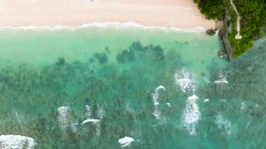 Dalgalar, yemyeşil orman ve kristal berrak turkuaz sularla çevrili beyaz bir kumsala nazikçe çarpıyor. Ilig Iligan Sahili. Boracay Adası, Filipinler.